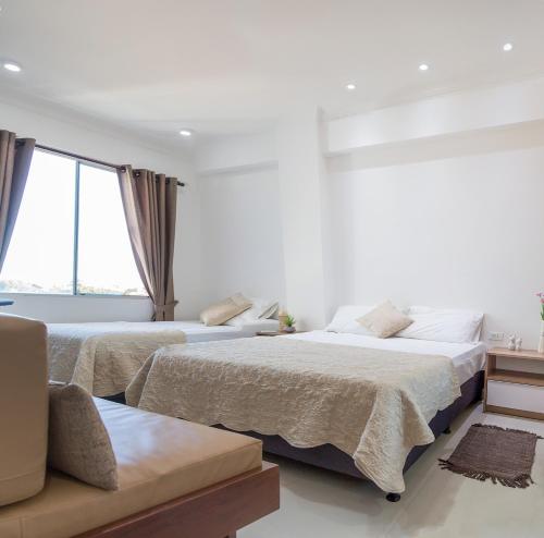 a white bedroom with two beds and a couch at DEPARTAMENTO FAMILIAR LAS PALMAS II in Santa Cruz de la Sierra