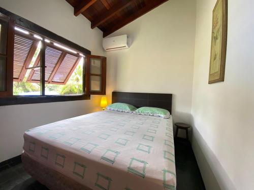 1 dormitorio con 1 cama grande y ventana en Casa Vento Norte en Ilhabela