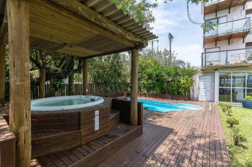 een hot tub in een houten terras met een pergola bij Apto pé na areia com vista p/ mar JBM in Florianópolis