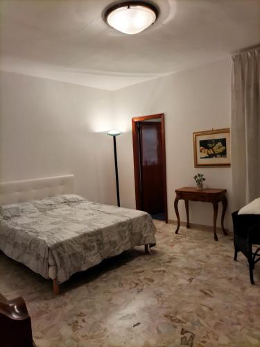 um quarto com uma cama, um candeeiro e uma mesa em Casa del Grillo in centro e nei pressi del mare em Catânia
