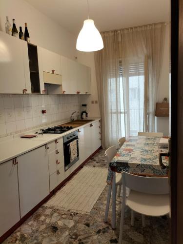uma cozinha com armários brancos e uma mesa com mesa; em Casa del Grillo in centro e nei pressi del mare em Catânia