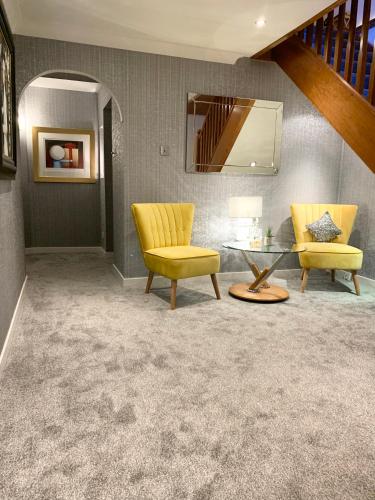 a living room with yellow chairs and a glass table at Ayrs and Graces - Luxury Bed and Breakfast in Ayr
