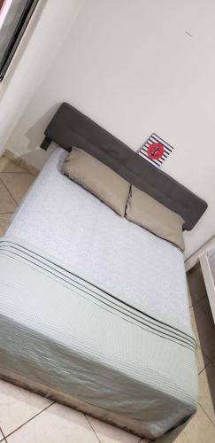 a white bed with a black headboard in a room at Mayda hostel in Praia Grande