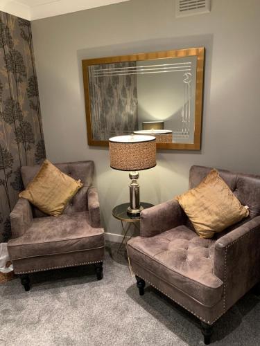 a living room with two chairs and a lamp and a mirror at Ayrs and Graces - Luxury Bed and Breakfast in Ayr