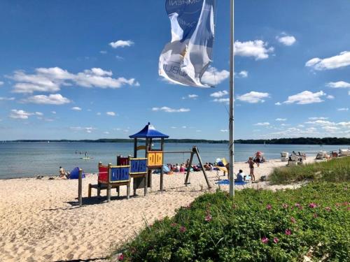 a flag on a beach with people in the water at Ferienwohnung "Leevhuus" in Glücksburg