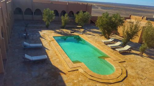 an overhead view of a swimming pool with chairs and a building at Kasbah Erg Chebbi in Merzouga