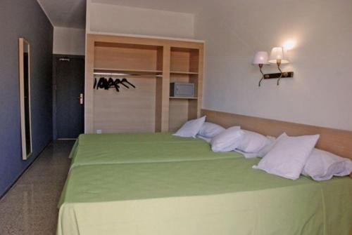 1 dormitorio con cama verde y almohadas blancas en Hotel Armonía, en Lloret de Mar