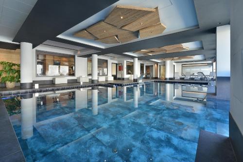 - une grande piscine avec des carreaux bleus dans un bâtiment dans l'établissement Hotel Bucaneve, à Livigno