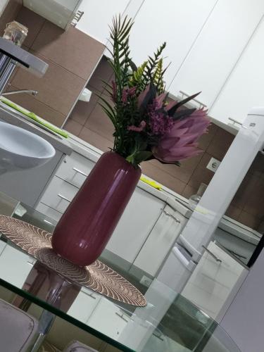 eine lila Vase mit Blumen auf einem Glastisch in der Unterkunft Downtown lux in Smederevo