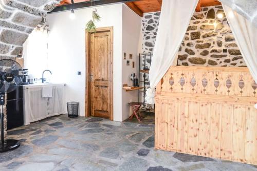 a kitchen with a wooden door and a stone wall at Volcano View Nisyros in Emporeiós