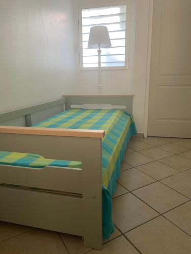 a bedroom with a bed with a lamp and a window at Ti Kaz Marigot in Terre-de-Haut