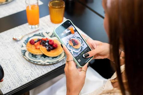 a woman taking a picture of a plate of food at InterContinental Porto - Palacio das Cardosas by IHG in Porto