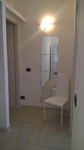 a room with a white chair and a mirror at Appartamento in centro paese in Monterosi
