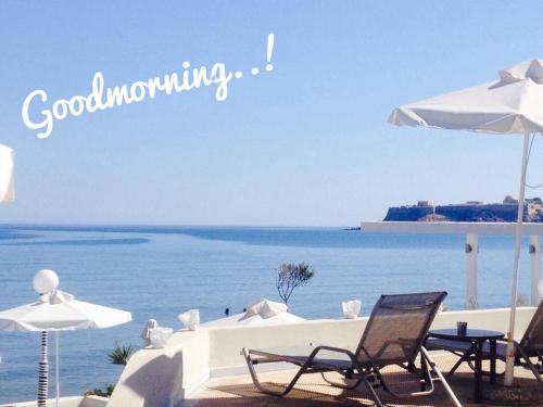 a beach with chairs and umbrellas and the ocean at Filoxenia Beach Hotel in Rethymno Town