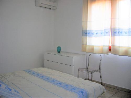 a bedroom with a bed and a chair and a dresser at Appartamento nel cuore di Villasimius 1 piano in Villasimius
