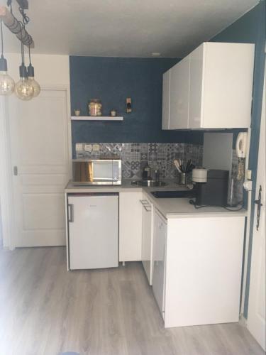 une cuisine avec des armoires blanches et un mur bleu dans l'établissement Studio Cosy à Orange, à Orange