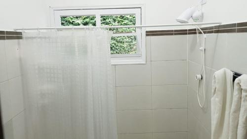 baño con cortina de ducha y ventana en Casa caiçara na Vila - Casa 01- Hospedaria da Vila, en Ilhabela