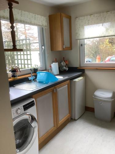 a kitchen with a sink and a washing machine at Croft cabin in Fort William