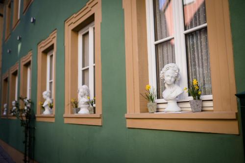 Hotel Belle Vue Volkach في فولكاخ: مبنى أخضر عليه نوافذ عليها تماثيل