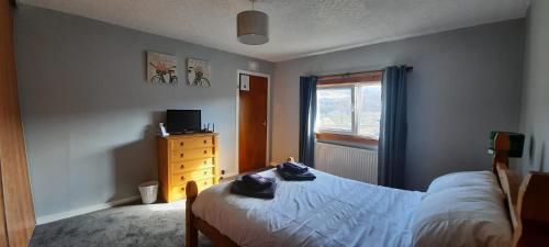 a bedroom with a bed and a dresser and a window at Taigh Thormoid in Amhuinnsuidhe