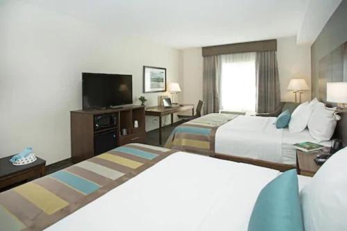a hotel room with two beds and a flat screen tv at Wingate by Wyndham Calgary Airport in Calgary