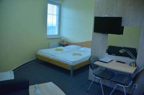 a room with a bed and a desk and a tv at Penzion ve věži in Bohumín
