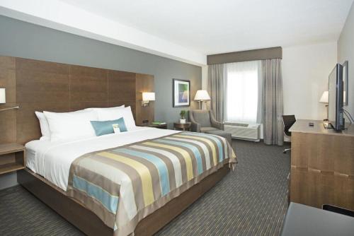 um quarto de hotel com uma cama e uma televisão em Wingate by Wyndham Calgary Airport em Calgary