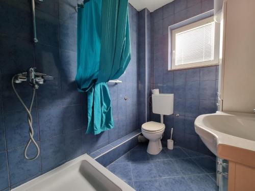 a blue tiled bathroom with a toilet and a sink at Apartment DIANA - Vidalići in Kustići