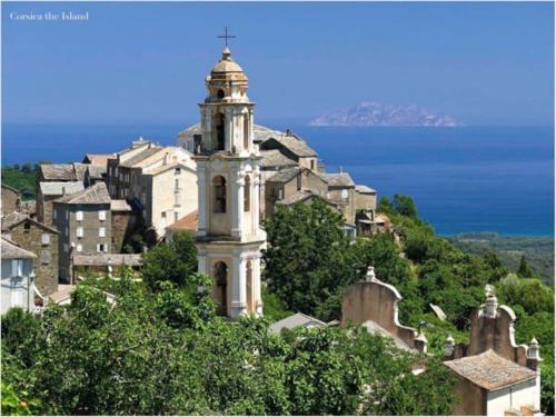 un bâtiment avec une tour au sommet d'une ville dans l'établissement Appartement 1 chambre en Haute-Corse à Pietra Di Verde, à Pietra-di-Verde