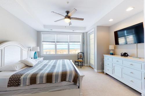 a bedroom with a bed and a ceiling fan at The Sandbridge Dunes - Salty Mermaid 110 in Virginia Beach