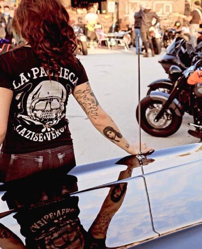 a woman with tattoos on her arm standing next to a motorcycle at La pacheca in Lazise