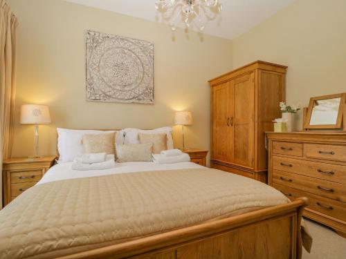 ein Schlafzimmer mit einem großen Bett und einer Kommode in der Unterkunft Garden Cottage in Keswick