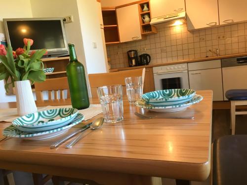 a wooden table with two plates and a bottle of wine at Knirschenhof in Windischgarsten