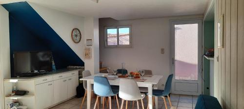 eine Küche mit einem weißen Tisch und blauen Stühlen in der Unterkunft Maison de village 4 à 6 pers à 5 min de la mer in Brétignolles-sur-Mer