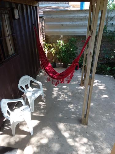 two white chairs and a hammock on a porch at Recuerdos in Atlántida