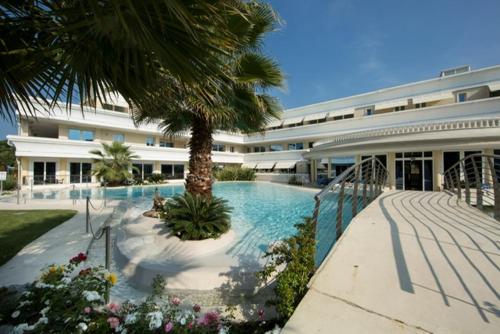 duży budynek z basenem i palmą w obiekcie Appartamento Du Lac 2 w mieście Desenzano del Garda
