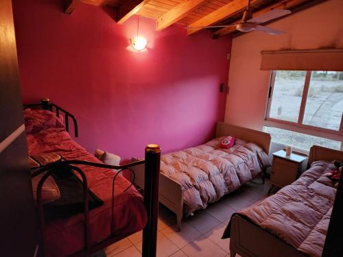 een slaapkamer met 2 bedden en een rode muur bij Casa quinta en Pocito con pileta quincho cancha de futbol in Pocito