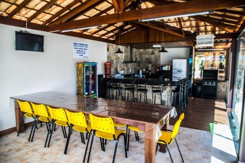 a wooden table and yellow chairs in a restaurant at A Fazenda eventos e lazer Lindomar Gonçalves in Piumhi
