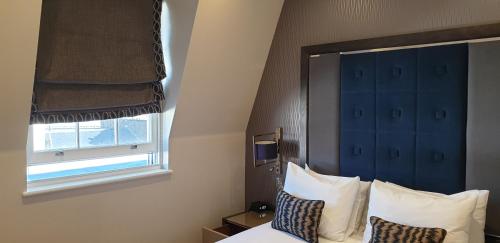 a bedroom with a bed with pillows and a window at The Westbourne Hyde Park in London