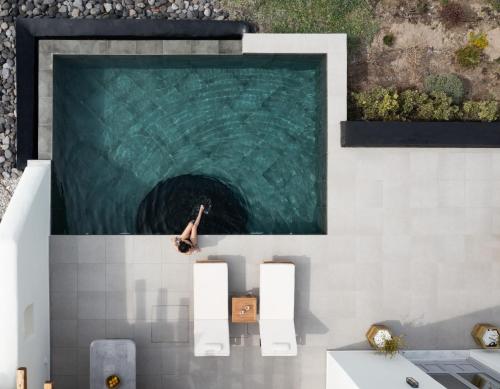 una piscina con una persona en el agua en Saint John Oia-The Ultimate Private Heated Pool Villas, en Oia
