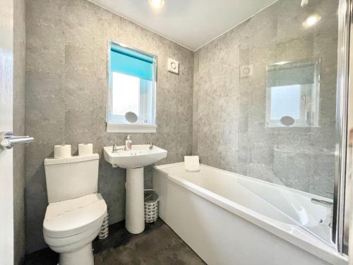 W łazience znajduje się toaleta, umywalka i wanna. w obiekcie Hazel House - Vibrant 2 bed house in Wishaw w mieście Wishaw