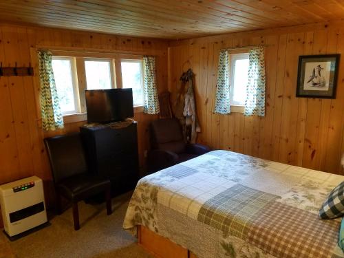 a bedroom with a bed and a chair and windows at Northwoods Cottage Bed and Breakfast in Fairbanks