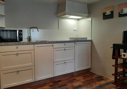 a kitchen with white cabinets and a sink at Gastenverblijf 't Nagtegaeltje in Sint-Oedenrode