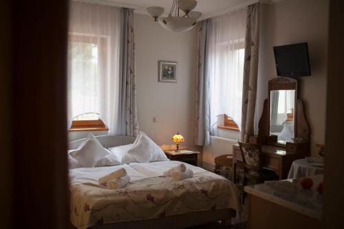 - une chambre avec un lit doté de draps et d'oreillers blancs dans l'établissement LuDo Apartman Hotel & Spa, à Makó