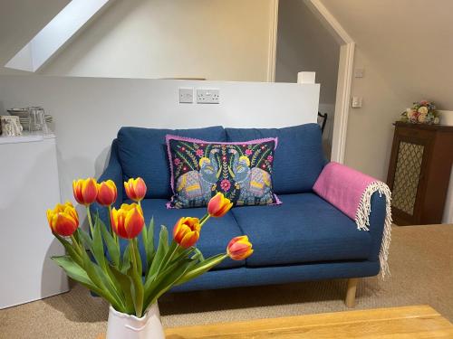 The Hayloft B and B في نيوبري: أريكة زرقاء مع إناء من الزهور في غرفة المعيشة