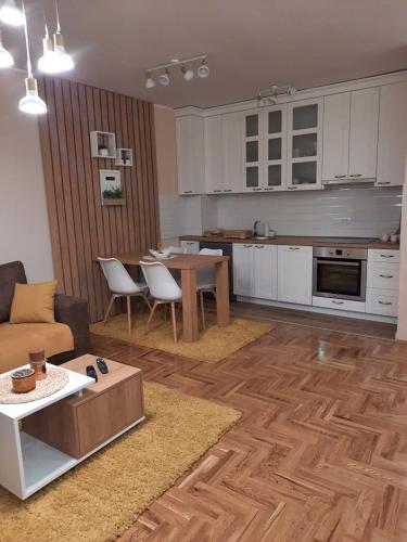 a kitchen and a living room with a couch and a table at Apartman Ljiljana LUX Sombor in Sombor