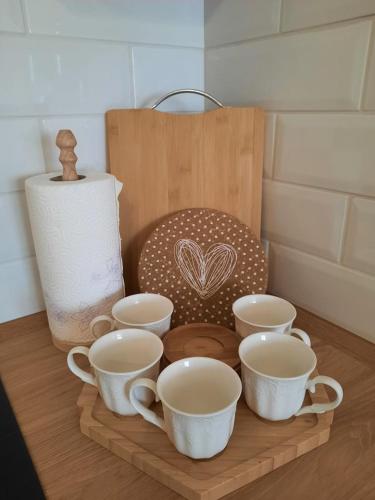 a wooden tray with four cups on a table at Apartman Ljiljana LUX Sombor in Sombor