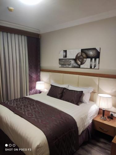 a hotel room with a large bed and two lamps at Altelal Tower Apartment in Mecca