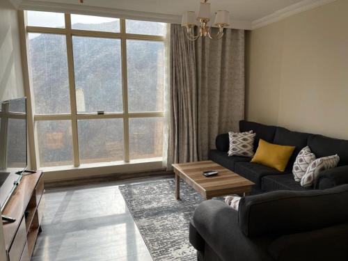 a living room with a couch and a large window at Altelal Tower Apartment in Makkah