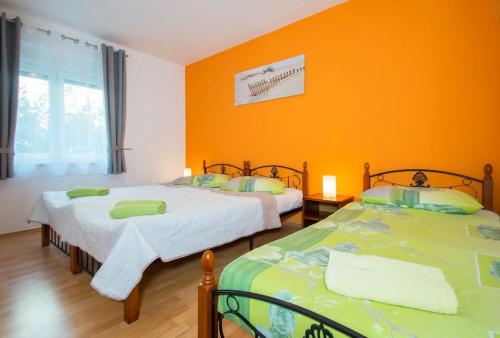 2 Betten in einem Zimmer mit orangefarbener Wand in der Unterkunft Holiday House Jagoda in Labin